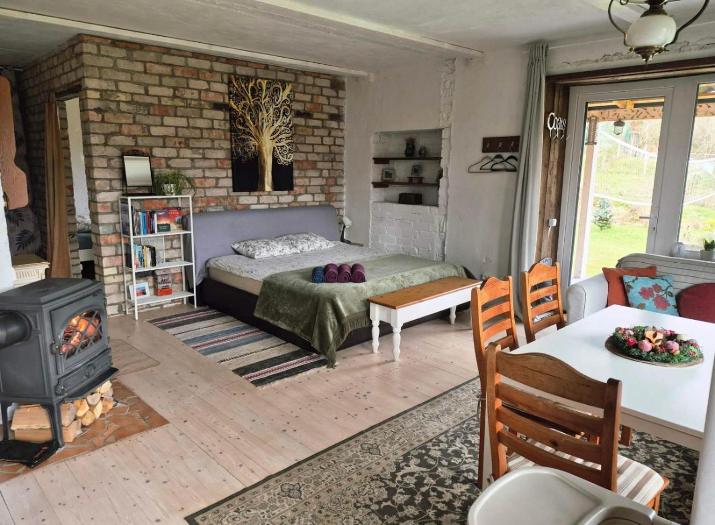 Apartamentai su dvigule lova, plytų siena ir degančia malkine krosnele